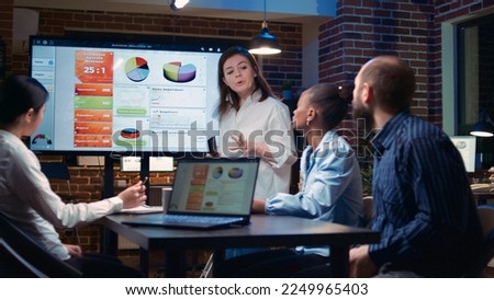 Business analytics team meeting, woman showing corporate presentation, marketing strategy planning. Sale statistics diagrams at digital board, coworkers brainstorming in office