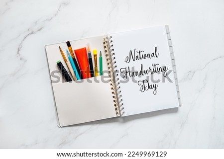 National Handwriting Day, 23 january. Hand lettering inscription text on paper notepad with pens and pencils on the table