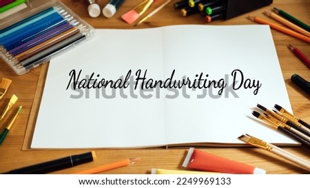National Handwriting Day, 23 january. Hand lettering inscription text on paper notepad with pens and pencils on the table
