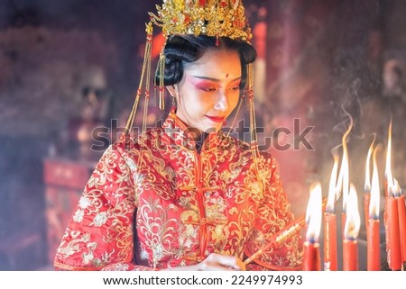 Woman traditional dress in Chinese shrine light up candle joss stick pray in temple