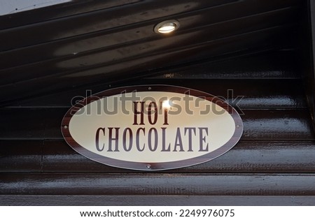 Close Up of Oval Metal Sign 'Hot Chocolate'  on Side of Wooden Cabin 