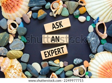 Ask an expert symbol. Concept words Ask an expert on wooden blocks on a beautiful black table black background. Sea shell and stone. Business and ask an expert concept. Copy space.