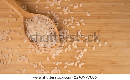 Grains Of Rice On A Wooden Floor, Top View. Raw Rice in Wooden Spoon For Menu Concept, Copy Space.