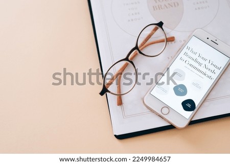 A beautiful glasses is placed with white mobile placed on a note book