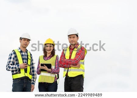 Photo of a team of 3 engineers or architects, man and woman smiling, standing together in strength and unity. Wear uniforms and helmets. Cool and smart, ready to work on industrial structures