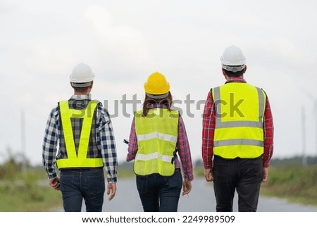 A behind-the-scenes photo of a team of 3 engineers or architects wearing uniforms and helmets. walk to the path ahead Look at the power and bright future and unity together. on one street