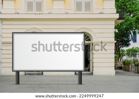 Large horizontal blank advertising poster billboard banner mockup in front of building in urban city; digital light box display screen for OOH media. 12 sheet out-of-home Royalty-Free Stock Photo #2249999247