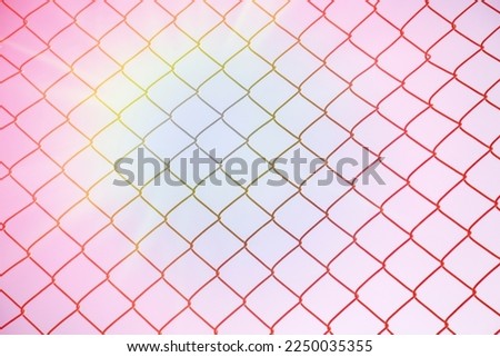 A closeup of a fence that is protecting a property. The metal gate isolated with pink and sunny background 