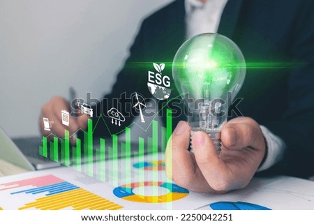 ESG environment concept. Businessman holding light bulb starting from a new idea and using a laptop computer for investment with vitual ESG environmental icon. business strategy investing.