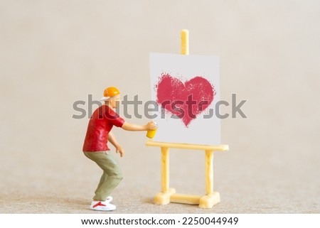 Miniature people, Artist holding dispenser and spraying with red heart shapes, Valentine day concept