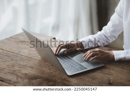 Person typing on laptop keyboard, businessman working on laptop, he is typing messages to colleagues and making financial information sheet to sum up the meeting. Royalty-Free Stock Photo #2250045147