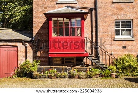 Horizontal shot of  old courtyard with redbrick house and iron steps leading to a red porch