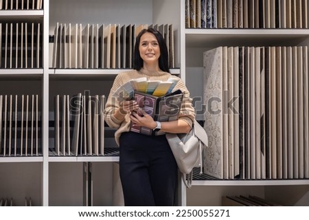 Adorable woman interior designer select grout epoxy ceramic tiles indoor finishing works at renovation store. Female professional architect decorator choosing materials for wall floor design at shop Royalty-Free Stock Photo #2250055271