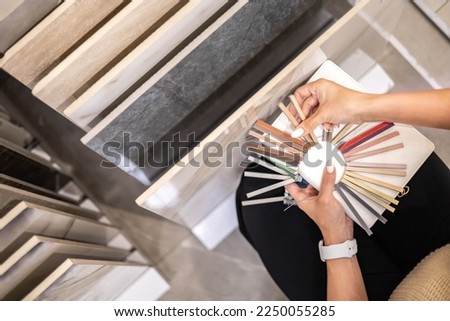 Female designer hands choosing epoxy grout compare with ceramic tile indoor architecture decoration closeup. Woman arms choice selection room furnishing materials creative professional architect Royalty-Free Stock Photo #2250055285