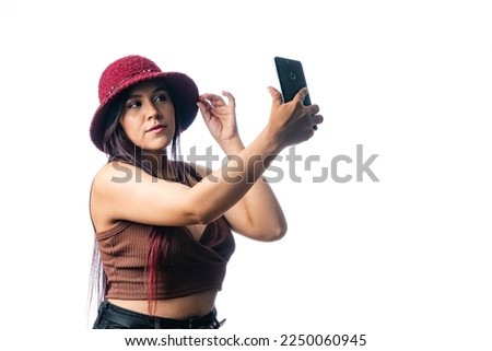 young woman shopping for clothes and seeing how it looks. girl taking a picture with her phone. vanity expression on white background