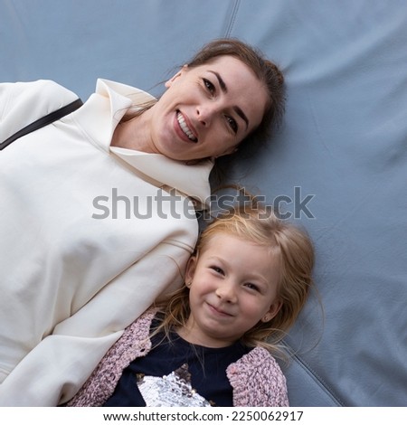 Smiling mom and preschool daughter lying on their back. Top view, flat lay.