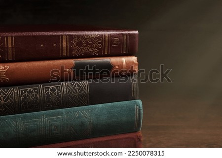 Stack of old hardcover books on wooden table, closeup. Space for text