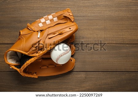 Leather baseball glove with ball on wooden table, top view. Space for text