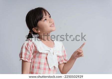 Portrait of child girl with finger pointed up. Little kid in pose has idea isolated on white blackboard. Success, bright idea, creative ideas and innovation technology concept
