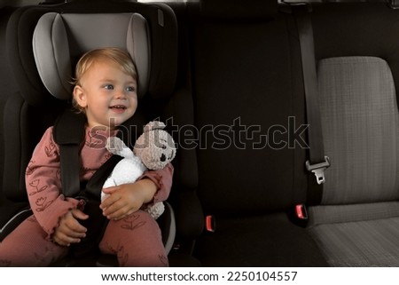 Cute little girl sitting in child safety seat inside car Royalty-Free Stock Photo #2250104557