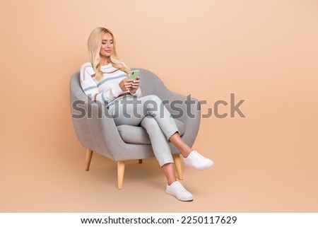 Full body size photo cadre of mature aged attractive lady hold phone freelance tasks customer sit comfort chair isolated on beige color background