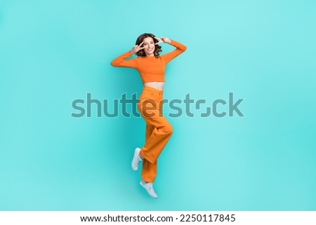 Full length photo of overjoyed lady wear orange clothes show v-sign have fun good mood isolated on cyan color background