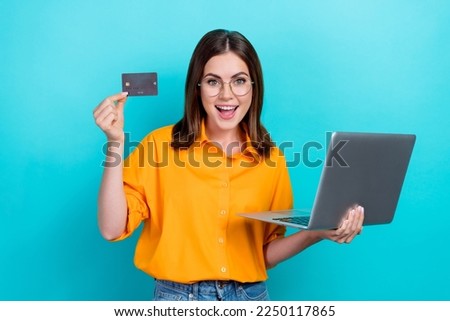 Photo of impressed excited cheerful woman with straight hairdo wear yellow shirt hold laptop debit card isolated on teal color background