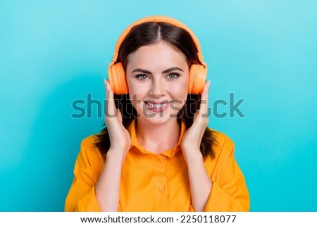 Photo of pretty charming lady wear orange shirt listening songs earphones isolated turquoise color background