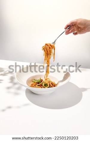 Woman eat italian pasta with tomato and basil. Female hand holding fork with spaghetti over dish. Eating pasta. Person eat italian food. Stretching pasta with woman young hand Royalty-Free Stock Photo #2250120203
