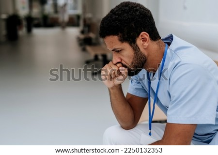 Young distressed doctor sitting at hospital corridor floor. Royalty-Free Stock Photo #2250132353
