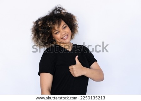 Joyful woman showing thumbs up. Young female model expressing positive opinion with gesture. Portrait, studio shot, support concept