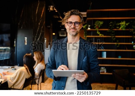 Mature manager using tablet computer during offline meeting in office Royalty-Free Stock Photo #2250135729