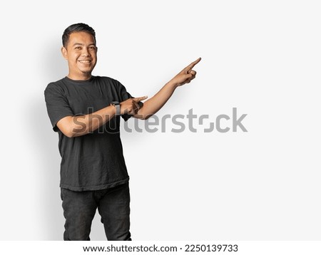 Asian man set pointing his finger in left up direction with two hands. A casual people use black t-shirt with joyful emotions pointing looking at camera. photo with white flat background. image asset