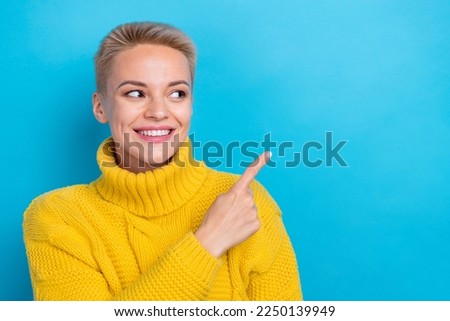Photo of positive gorgeous lady wear cozy yellow outfit arm direct empty space presenting novelty isolated on blue color background