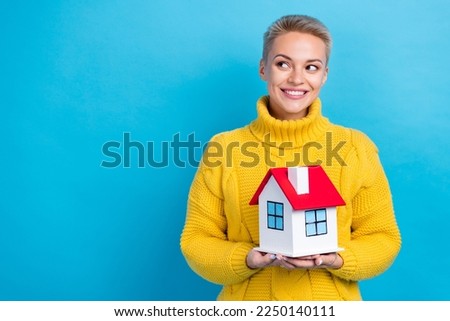 Photo of positive new ownership cute blonde short hair girl wear yellow jumper look empty space hold house no loan isolated on blue color background
