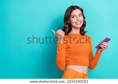 Photo of glamour funny charming lady stylish orange clothes arm direct empty space modern technology isolated on cyan color background