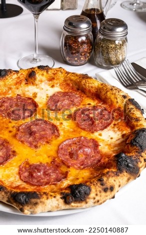 Salami pizza, accompanied by dishes and wine on a restaurant table. Salmi pizza. Italian food
