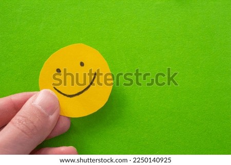 Hand holding paper with smiley face drawn on it. Mental health and positivity concept photo with copy space.