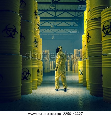 man in yellow protective suit in warehouse with metal drums with radioactive and chemical waste. Royalty-Free Stock Photo #2250143327