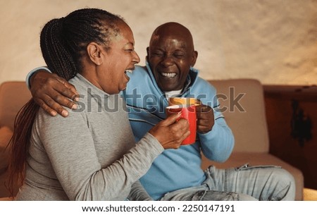 Happy senior african couple having fun drinking hot chocolate together at home