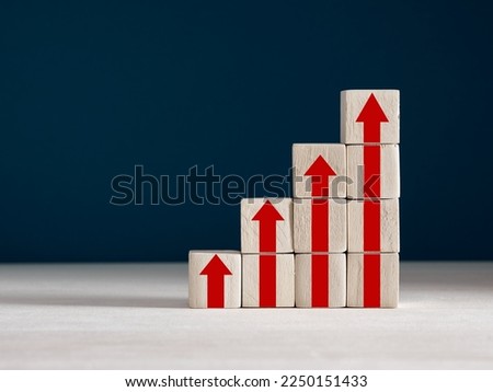 Stack of wooden cubes with red arrows going up. The process of successful business development, economy, increasing productivity, performance and profit concept. Royalty-Free Stock Photo #2250151433