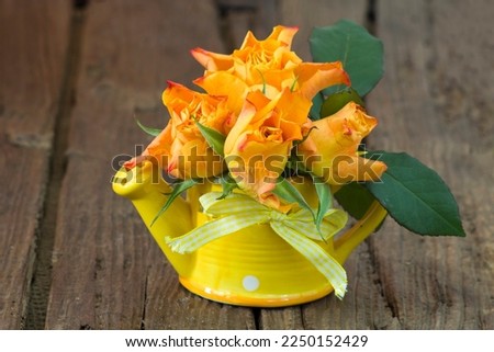 orange roses in a vase on wooden background