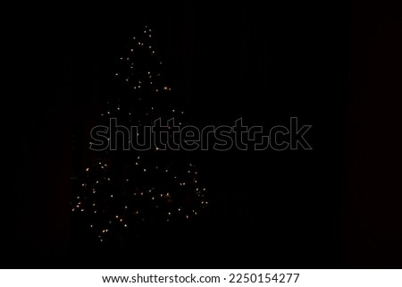 Abstract background of blurred yellow lights, Christmas tree silhouette. Lights bokeh dis focus. Christmas background, copy space