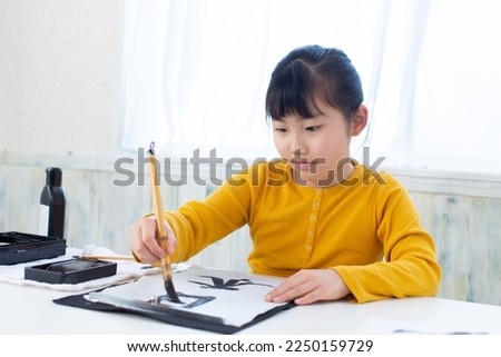 A Japanese girl practicing Japanese calligraphy Royalty-Free Stock Photo #2250159729