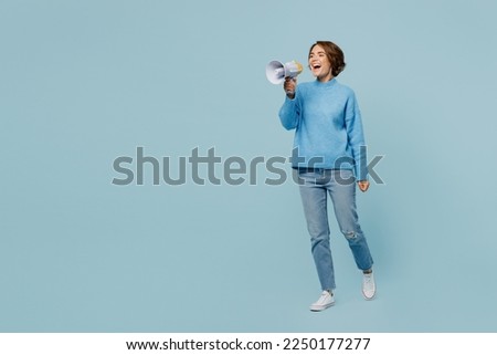 Full body shocked excited fun happy young woman wear knitted sweater hold in hand megaphone scream announces discounts sale Hurry up isolated on plain pastel light blue cyan background studio portrait
