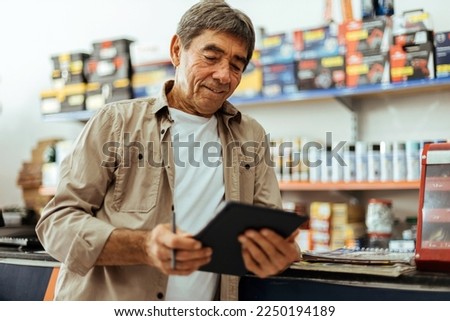 Elderly man working in a hardware store using digital tablet. Small business concept. Royalty-Free Stock Photo #2250194189