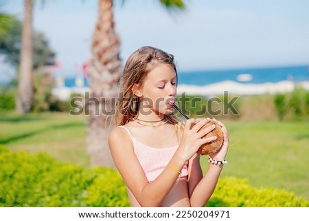 Happy girl in bikini drinking coconut milk on the beach