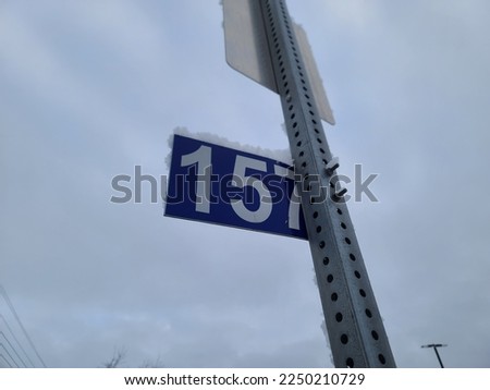 A closeup of the civic  number 157 that is attached to a metal pole.