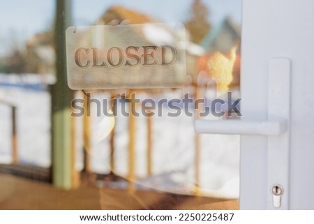 wooden sign with inscription closed at glass entrance door. working hours of the restaurant or office. welcome we are opening. cozy cafeteria or coworking