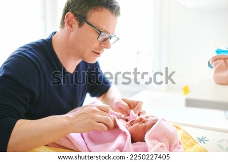 Father taking care of newborn baby, drying kid with towel after bathtime